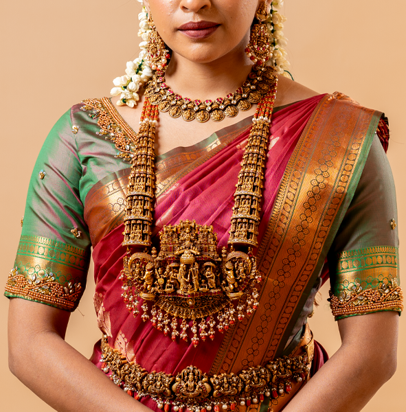 A woman wearing a traditional saree with gold-plated silver jewelry on a beige background