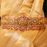 Decorative gold belt with red and green stones on a gold fabric background